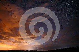 Night Starry Sky With Glowing Stars And Meteoric Track Trail Above Countryside Landscape. Light Cloudiness Overcast