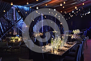 Night table set for dining and flowers decoration with candles at night, indoor luxury wedding with low light romantic ambient