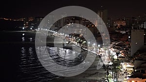 Night time El Campello Spain with sparkling lights, palm trees, sea and distant people