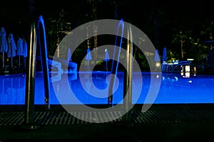 Night time pool handrails in the hotel water is blue