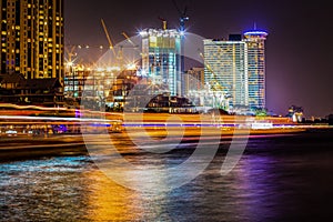 Night time skyline with high buidings by the Chao Praya river in Bangkok, Thailand.