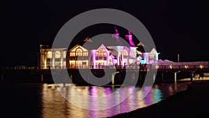 Night Timelapse Of Lift Sellin Pier Colorful Illumination is Reflected in Calm Sea Water