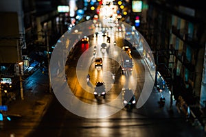 Night traffic in Bangkok. People cross the street at a pedestrian crossing. Car headlights are out of focus in the background