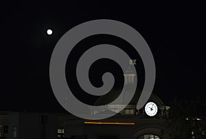 Night urban landscape, round the clock and the full moon.