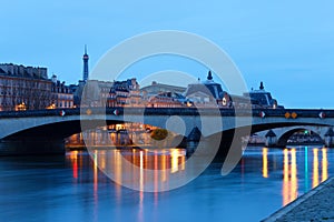Night view of the banks of the Seine in Paris, France, with Carrousel bridge , Ouai Voltaire and beautiful sky and