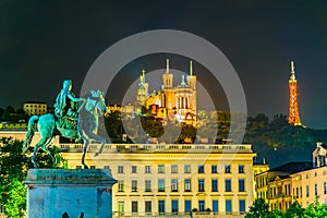 Night view of Basilica Notre-Dame de Fourviere viewed behind statue of Louis XIV in Lyon, France