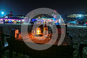 Night beach party in cafe with bottle of rose wine and glasses in GOA, India