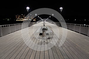 Night view of a boardwalk, bench and lamp posts