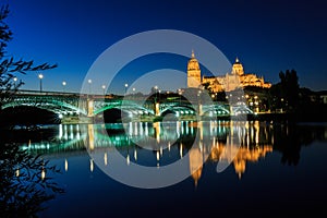 Night view of the Cathedral of Salamanca with Enrique Esteban bridge lit foreground and reflections in the Tormes river, Salamanca photo
