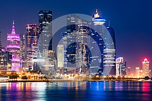 Night view on the centre of the city Doha, Qatar with many modern luxury building and skyscrapers illuminated with bright lights