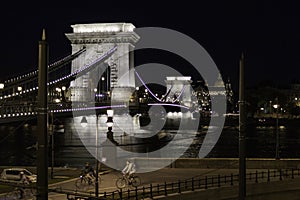 Night view of the Chain Bridge with cyclists walking the streets of Budapest, Hungary photo