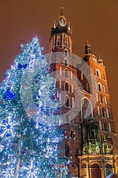 Night view of a Christmas tree and St. Mary\'s Basilica at the medieval square Rynek Glowny in Krakow, Pola