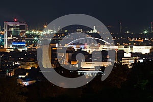 Night view on the city. Red lights, buildings, bridge and factory