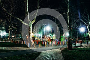 Night view of a colorful playground among park trees in a residential area of Anapa.