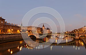 Night view of Conciergerie Castle and Pont Notre-Dame bridge over river Seine. Castle Conciergerie is a former prison