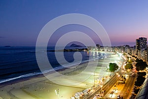 Night view of Copacabana beach during sunset in early evening, taken from the rooftop of a hotel, sky is purple and the nightlife