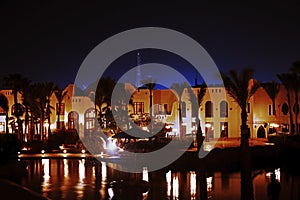 Night view at egyptian buildings with palms and swimming pool