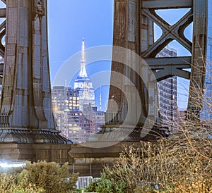 Night view of the Empire State Building through the pylons of Manhattan Bridge. View from Washington Street in Dumbo