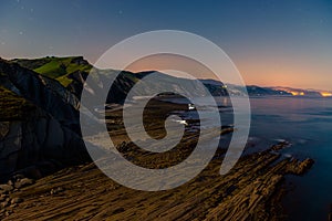 Night view of flysch and shellfishermen with low tide and full moonlight in Zumaia