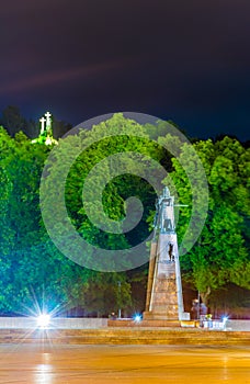 Night view of the Grand Duke Gediminas statue seen on Katedros Square in Vilnius with the three crosses hill behind it