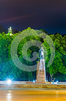 Night view of the Grand Duke Gediminas statue seen on Katedros Square in Vilnius with the three crosses hill behind it