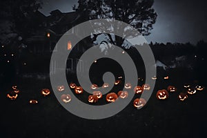 night view of home exterior decorated for halloween holiday, jack o lanterns in the yard
