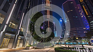 Night view hyperlapse of modern city in park with fountain and skyscrapers around. Time lapse. Hong Kong