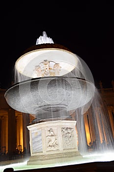 Night view of the illuminated fountains in St. Peter`s Square with the basilica in the background with no people. Travel concept