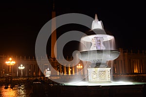 Night view of the illuminated fountains in St. Peter`s Square with the basilica in the background. Travel concept