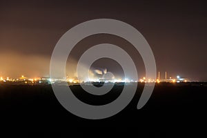 Night view of industrial district of city and smoke pipes of factory