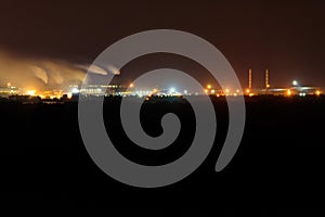 Night view of industrial district of city and smoke pipes of factory