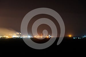 Night view of industrial district of city and smoke pipes of factory