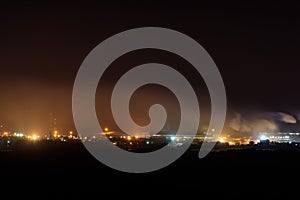 Night view of industrial district of city and smoke pipes of factory