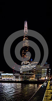 Night view of London skyscraper The Shard, office buildings, London Bridge hospital and tourists taking photos from the bridge to