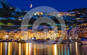 Night view of Marina Grande, Capri island, Italy. Illuminated streets of city are reflected in calm sea