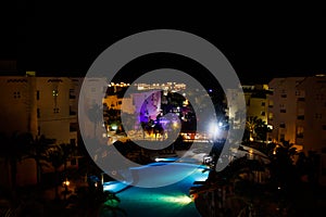 Night view of modern blue water swimming pool in tropical resort. View from above