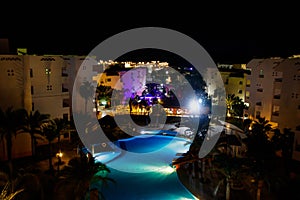 Night view of modern blue water swimming pool in tropical resort. View from above