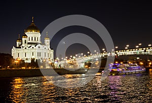 Night view of Moscow Christ the Savior Cathedral, Patriarshy Bridge, embankment and Moskva river with pleasure boat