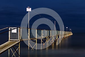 Night view of old wooden pier going into the sea