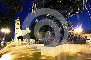 Night view of the Ornamental Pile,-water fountain with bronze sculptures in the background illuminated Cathedral of