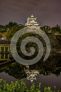 Night view of Osaka castle reflecting in water moat in Osaka, Japan