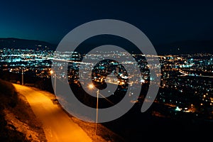 Night view from over capital of Georgia, Tbilisi. Street lights and hills surrounding the city. Blue sky. - Image