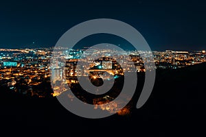 Night view from over capital of Georgia, Tbilisi. Street lights and hills surrounding the city. Blue sky. - Image