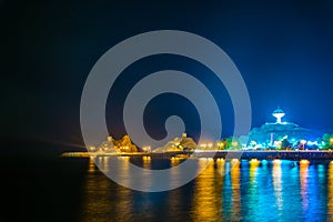 Night view of a peninsula in the Muttrah district in Muscat with the famous Al Riyam park and a watchtower on a steep cliff