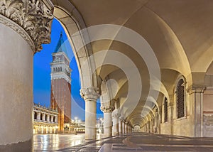Night view of Piazza San Marco with Doge`s Palace Palazzo Ducale columns and Campanile of Basilica in arch. Venice, Italy.