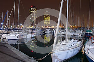 Night view of Port Olimpic harbor and marina in Olympic village in Barcelona. Mooring yachts, boats and other