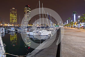 Night view of Port Olimpic harbor and marina in Olympic village in Barcelona. Mooring yachts, boats and other
