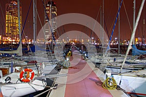 Night view of Port Olimpic harbor and marina in Olympic village in Barcelona. Mooring yachts, boats and other