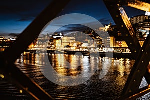 Night view of riverside in Porto with famous iron bridge in the front, Portugal