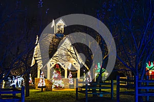 Night View Of A Small Chapel Decorated With Christmas Lights And Multiple Christmas Trees